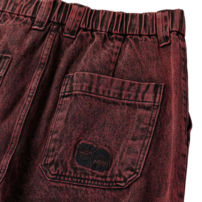 Close-up of maroon denim shorts with a pocket and brand logo.