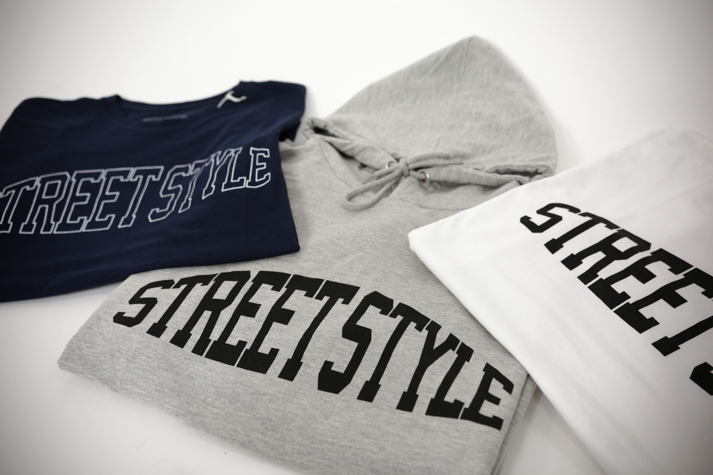 Show thumbnail preview
Three clothing items featuring the text "STREET STYLE": a navy blue T-shirt, a gray hoodie, and a white T-shirt. All are arranged on a plain background.