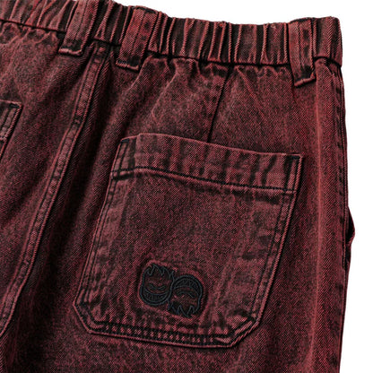 Close-up of maroon denim shorts with a pocket and brand logo.